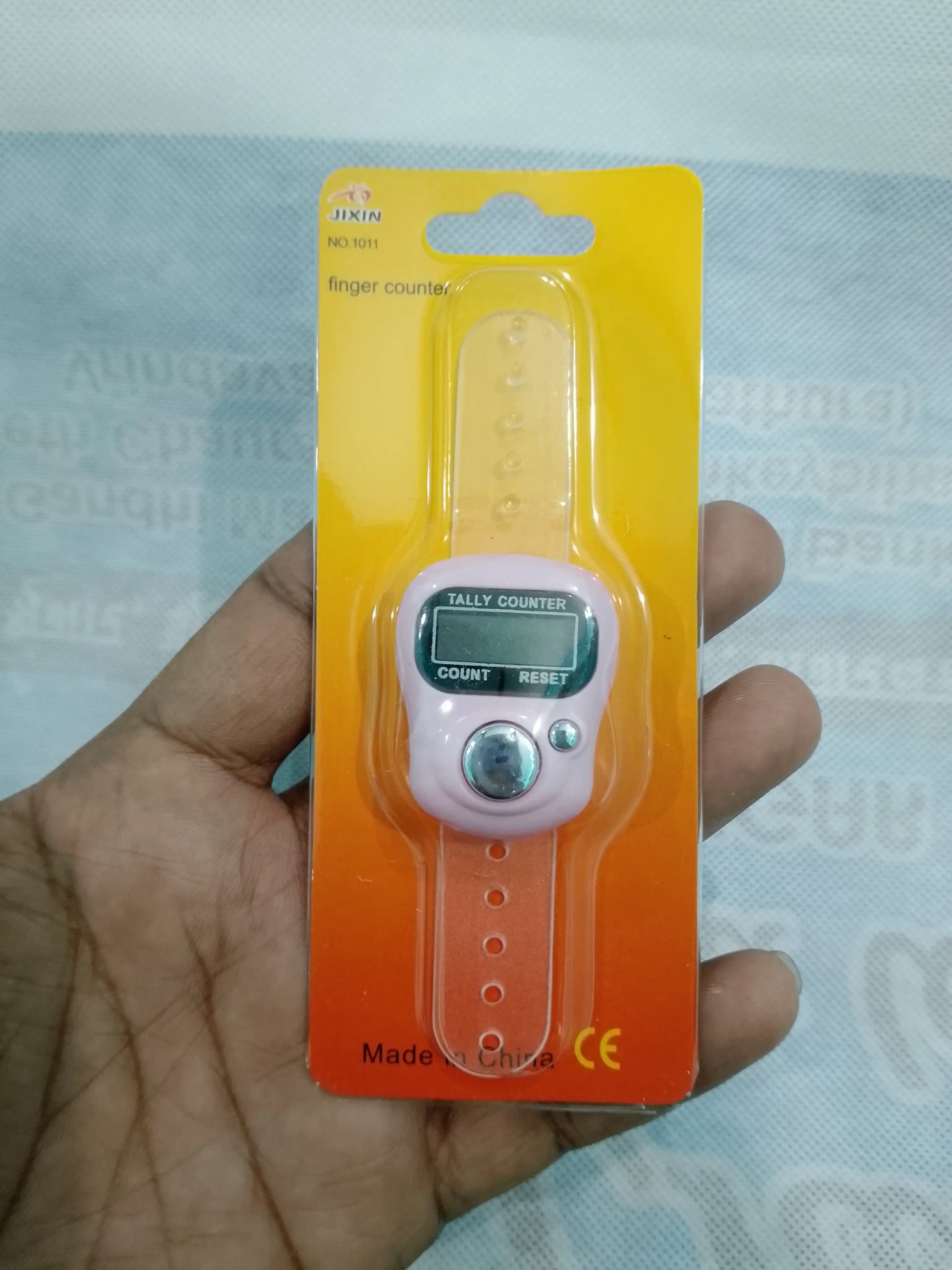 Tally counter on a yellow card held in a hand with a light blue textured background