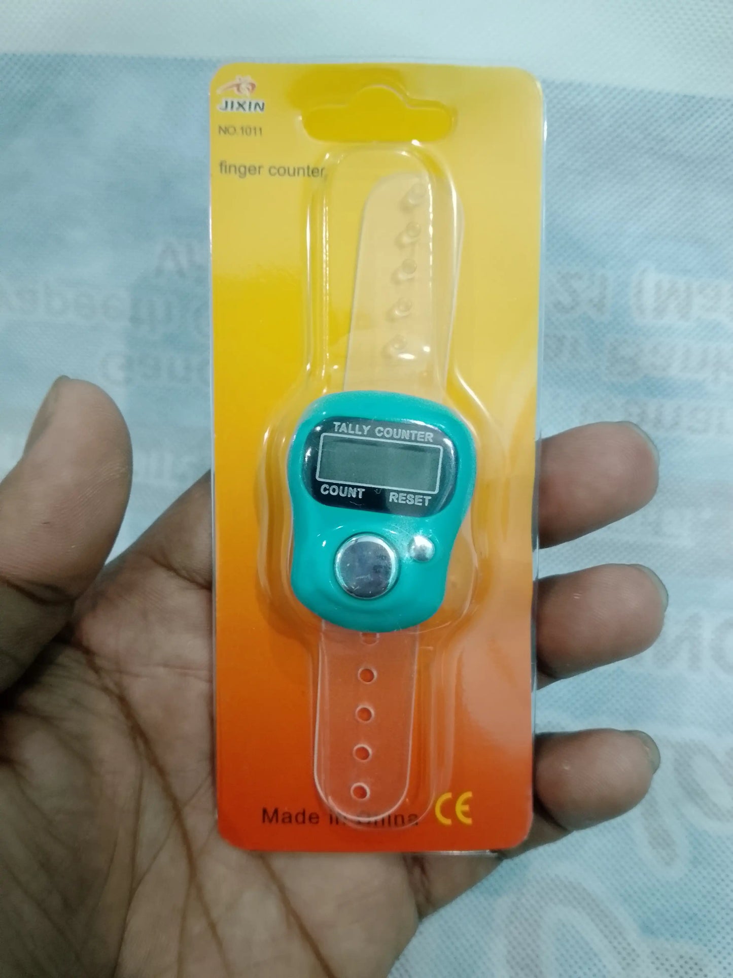 Digital finger counter on a hand with packaging in the background