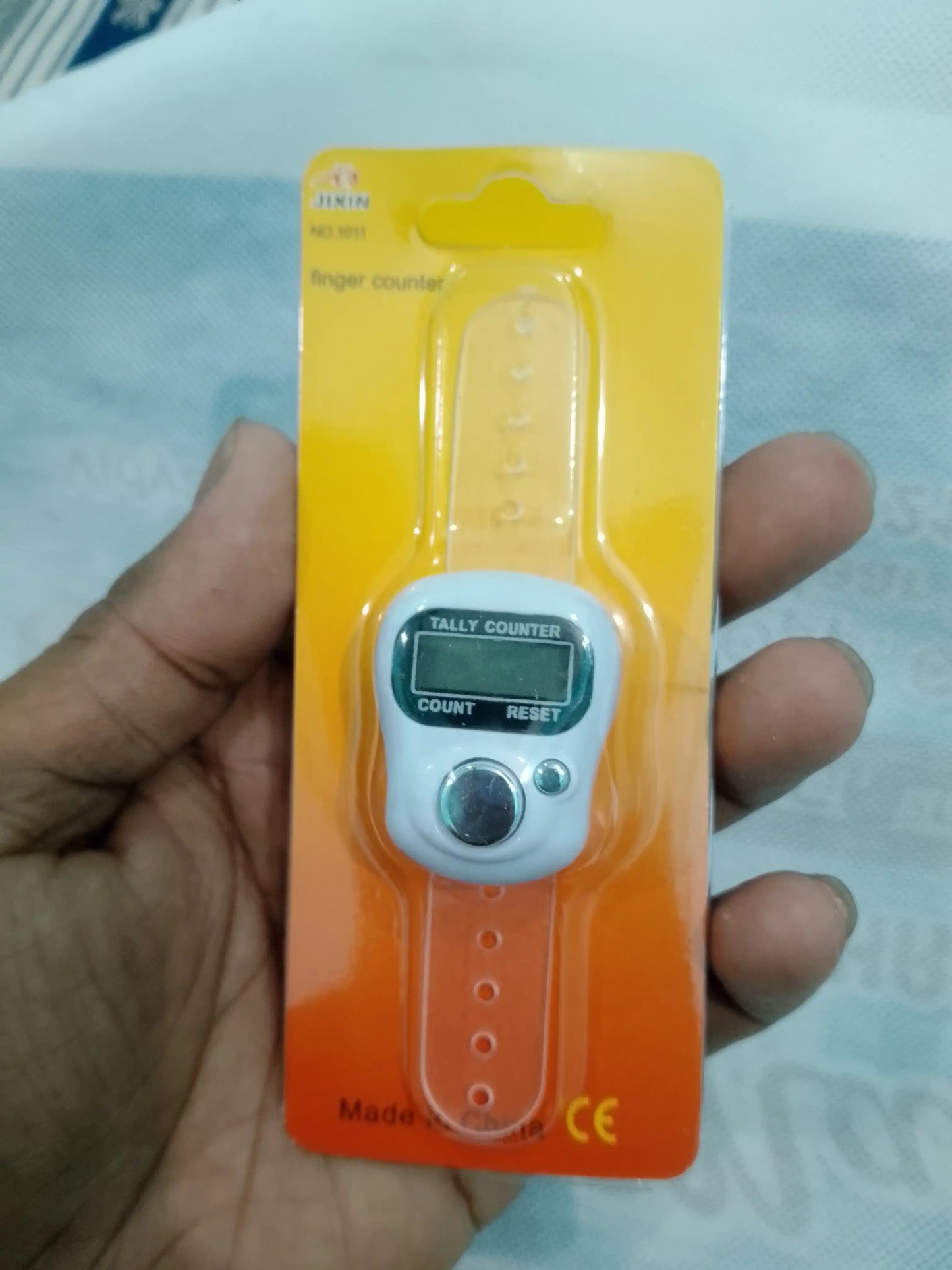 Digital tally counter on a card held by a hand with a light blue background