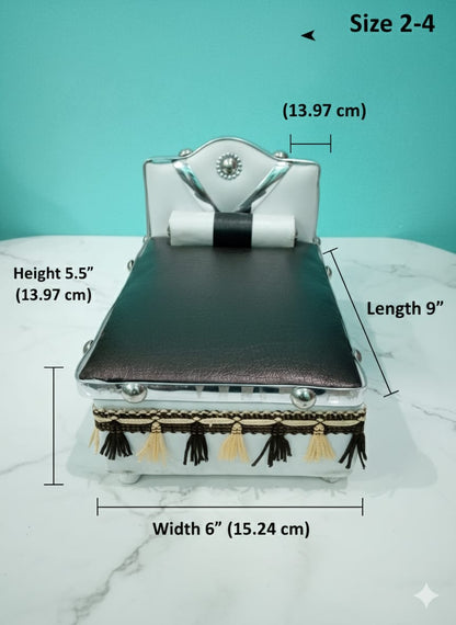 Silver Bed for Laddu Gopal Radha Krishna with black leather top and tassels on a white surface with teal background