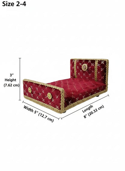 Red velvet bed with gold trim on a white surface against a teal background for Laddu gopal and Radha Krishna