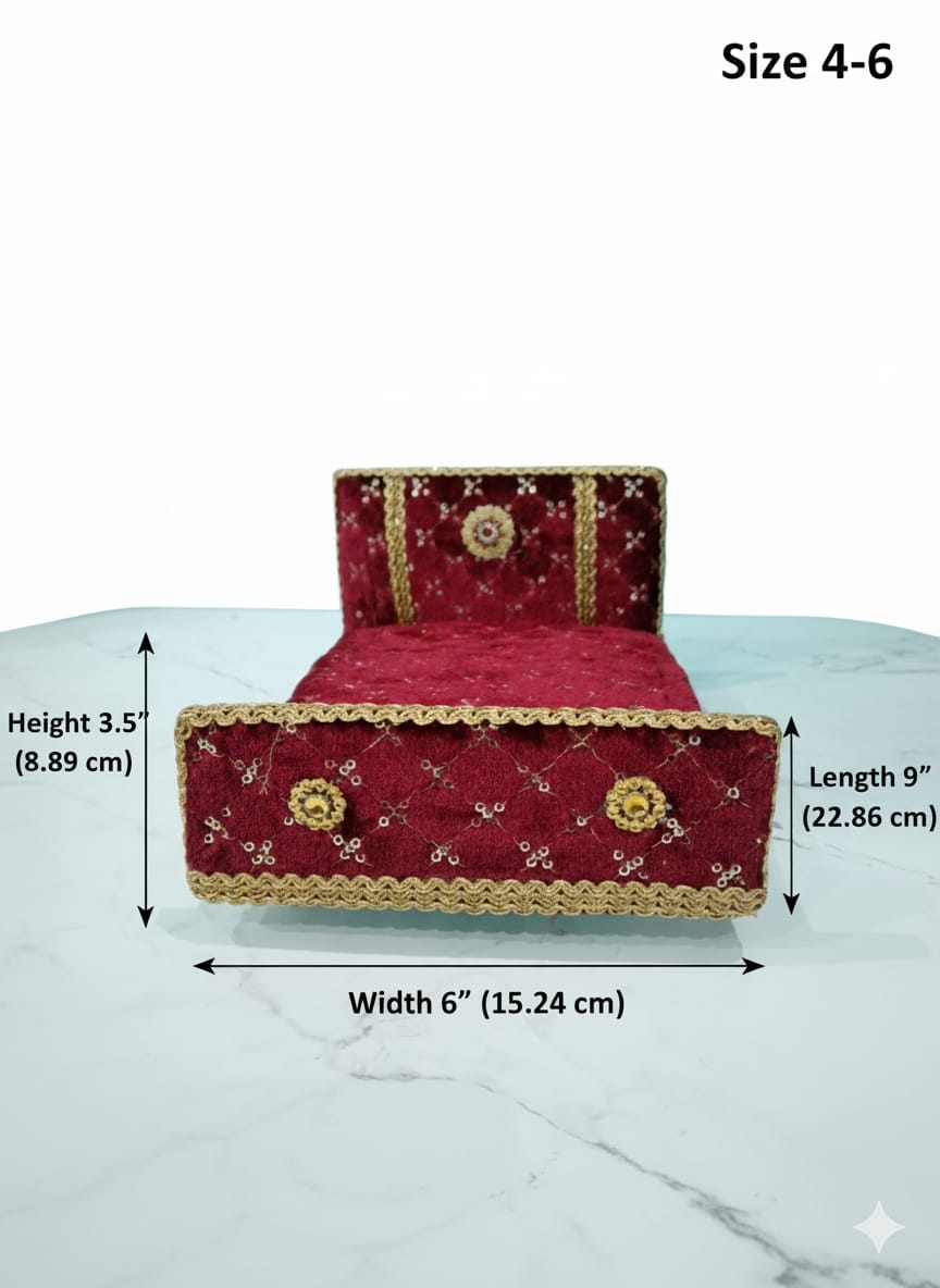 Red velvet bed with gold trim on a white surface against a teal background for Laddu gopal and Radha Krishna