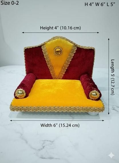 Singhasan for Gopal ji with red and yellow cushions on a white surface with teal background