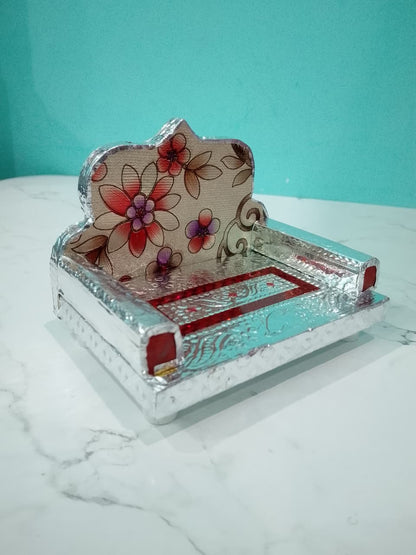 Laddu Gopal Pagdi with floral design on a marble surface against a teal background